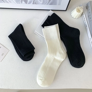 Macro view of ribbed cotton mid-calf socks in black and off-white colors
