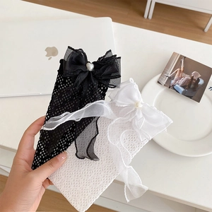 Gros plan de chaussettes résille avec grands nœuds en gaze et perles en forme de cœur