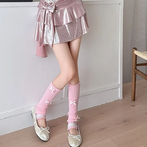 Pink rib-knit leg warmers with white satin bows paired with silver Mary Jane shoes