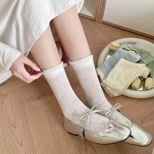 Detailed view of sweet Japanese style socks with pink bow patterns and white lace ruffles
