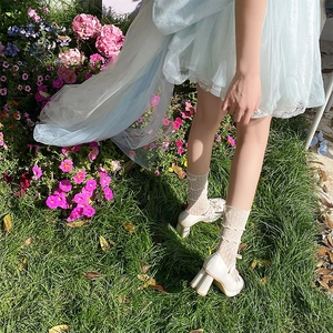 Détail de chaussettes en dentelle blanche avec motifs résille et chaussures Mary Jane sur l'herbe