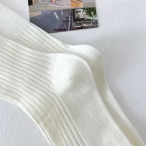 Detailed macro shot of white ribbed mid-calf socks with high elasticity cotton texture