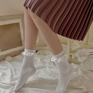 Close-up of white calf socks featuring satin ruffle trim and diamond texture patterns