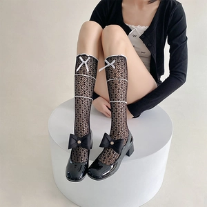 Détail de chaussettes en dentelle noire avec nœuds blancs et chaussures Mary Jane noires