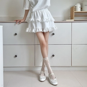 Détail d'une jupe blanche à dentelle avec chaussettes à nœud et ballerines douces