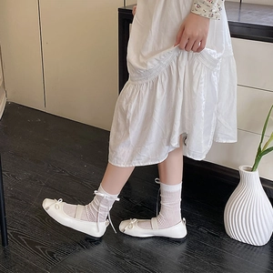 Detail of white ballet-style calf socks with delicate ribbon bows and striped texture
