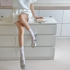 Détail de chaussettes rayées blanches à nœud et chaussures Mary Jane argentées