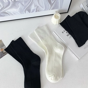 Detailed view of three pairs of ribbed cotton mid-tube socks in black and off-white