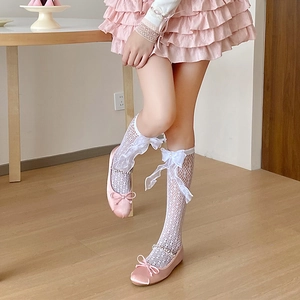 Détail de ballerines en satin rose avec chaussettes en dentelle blanche et gros nœuds