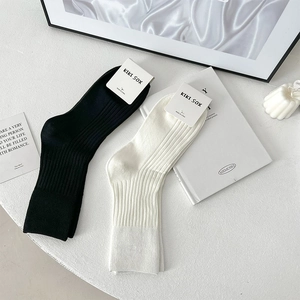 Detailed view of black and white ribbed cotton socks set with minimalist paper packaging