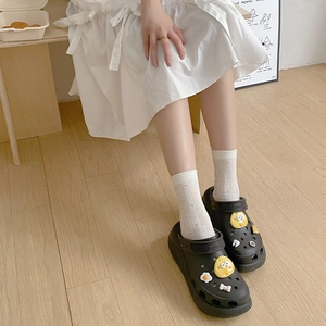 Gros plan de sabots à plateforme noirs avec charms et chaussettes blanches