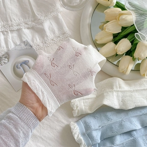 Detail of sheer white mesh socks with bow patterns and ruffled lace edges