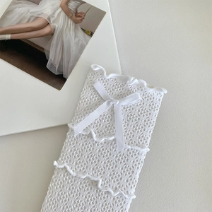 Détail de chaussettes en dentelle blanche avec motif ajouré et petit nœud en satin
