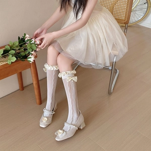 Détail de chaussettes hautes en dentelle avec nœuds en soie et perles au style Lolita