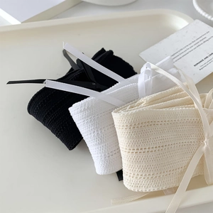 Détail de trois chaussettes en dentelle avec nœuds en noir blanc et beige sur plateau