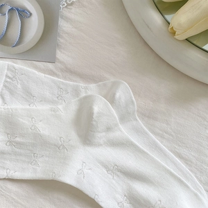 Detail of white knit socks featuring small bow patterns with soft breathable texture
