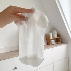 Détail d'une socquette blanche semi-transparente montrant la texture en maille respirante