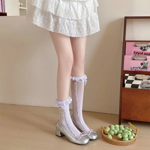 Détail de chaussettes hautes en dentelle blanche avec nœuds et chaussures Mary Jane