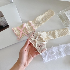 Détail de chaussettes en dentelle ajourée avec nœuds en satin et bords à volants