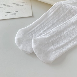 Gros plan de chaussettes en résille blanche avec rayures verticales et détails aérés
