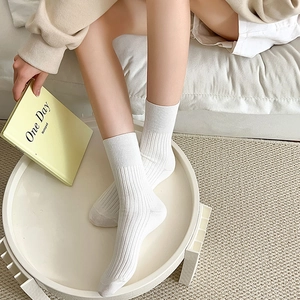 Close-up of white ribbed crew socks with vertical knit pattern worn in cozy home setting