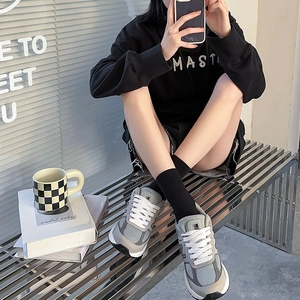 Close-up of retro grey patchwork sneakers with breathable mesh and suede texture on model