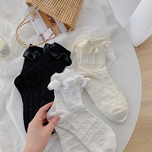 Detail of white Lolita style crew socks with lace ruffles, ribbons and diamond textures