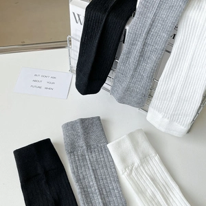 Detailed view of ribbed texture and elastic cuff on white, gray and black cotton calf socks