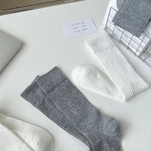 Vue détaillée de chaussettes en tricot côtelé gris et blanc sur un bureau blanc épuré