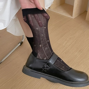 Détail de chaussettes mi-hautes noires transparentes avec motifs de petits cœurs