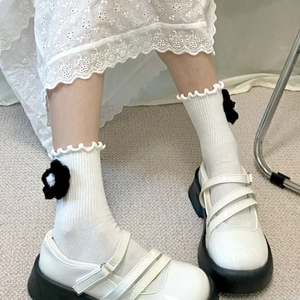 Detail of white ruffle socks with black flowers and platform Mary Jane shoes