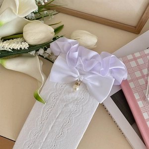 Détail de chaussettes en dentelle blanche avec nœud satiné et pendentif perle