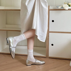 Close-up of white ruffle socks with pink bows paired with metallic silver Mary Jane shoes