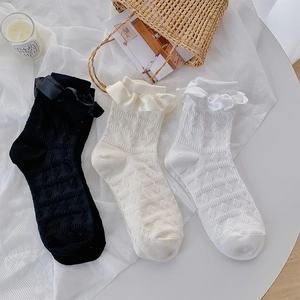 Detail of ruffled cuffs and satin bows on diamond-patterned knee-high socks