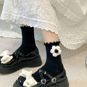 Detail of black crew socks with 3D crochet flowers and ruffled edges with Mary Janes