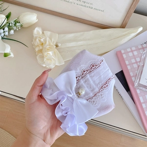 Détail de chaussettes en dentelle avec nœuds en satin et perle blanche décorative