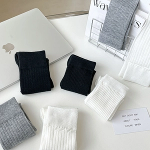 Détail de la maille côtelée des chaussettes en coton en noir, blanc et gris