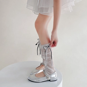 Dettaglio calzini in pizzo con fiocchi neri e scarpe Mary Jane argento con strass lucidi