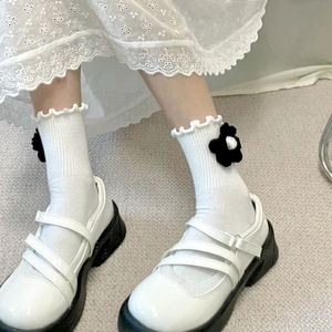 Close-up of white Mary Jane platform shoes with 3D floral crew socks and ruffle trim