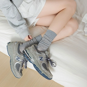 Détail de chaussettes en coton côtelé avec baskets en daim gris dans un cadre intérieur doux
