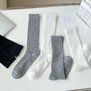 Flat lay of breathable ribbed cotton mid-calf socks in white, grey and black colors