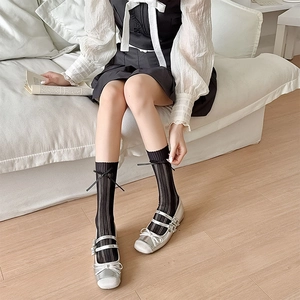 Détail de ballerines argentées à brides cristaux et chaussettes résille à nœud