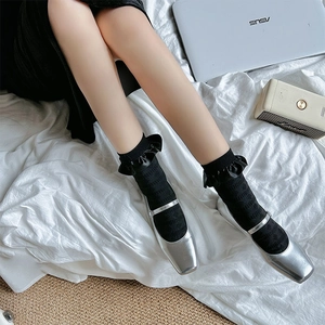 Detailed view of black ruffled knit socks paired with silver metallic Mary Jane flats
