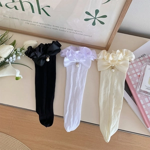 Détail de chaussettes en dentelle avec nœuds en satin et pendentifs en perles