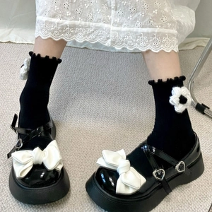 Detail of Mary Jane shoes with bows and ruffled socks featuring 3D knitted flowers