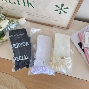 Détail de chaussettes en dentelle noires, violettes et beige avec nœuds et perles
