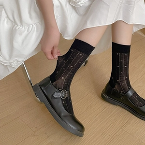 Détail de chaussettes noires à motifs cœurs et nœuds avec chaussures Mary Jane