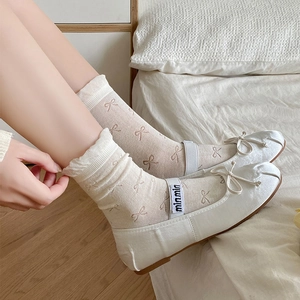 Detail of white Mary Jane flats with ribbon bows and matching pink bow knit socks