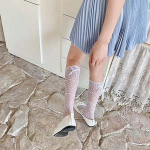 Détail de chaussettes hautes en dentelle blanche avec nœuds et maille losange ajourée