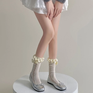 Détail de chaussettes en dentelle blanche avec nœud perlé et ballerines argentées